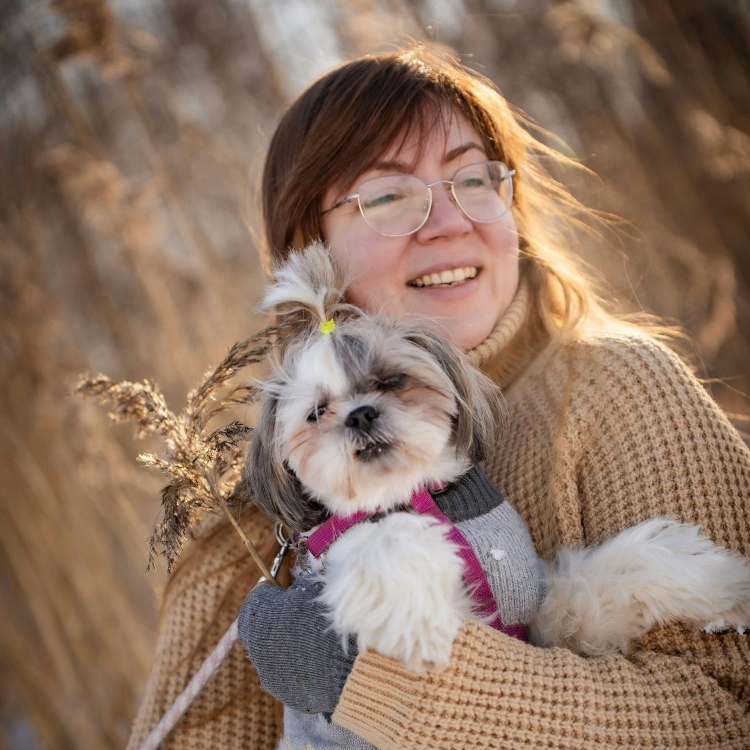 a person is holding a small dog in their arms