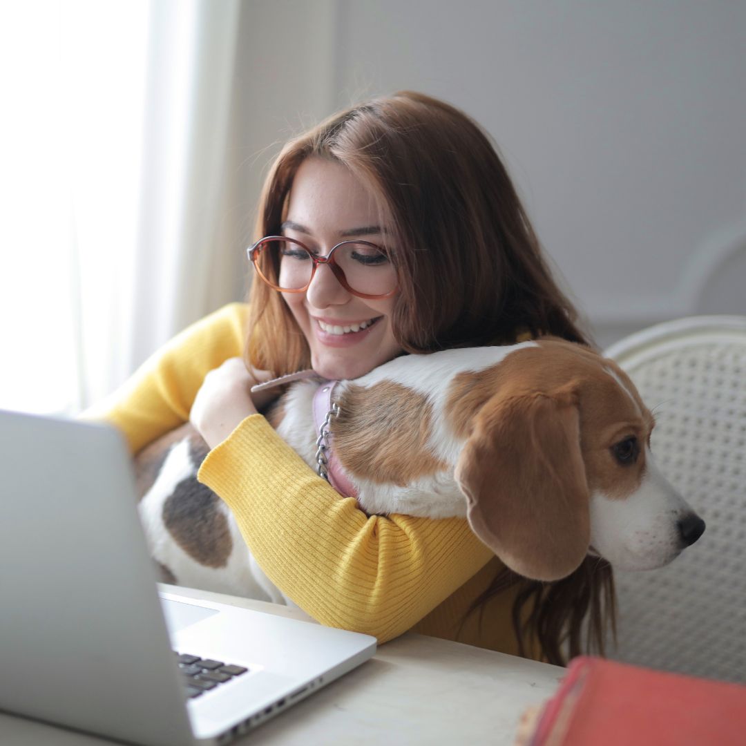 a person with glasses and a dog sitting in front of a laptop